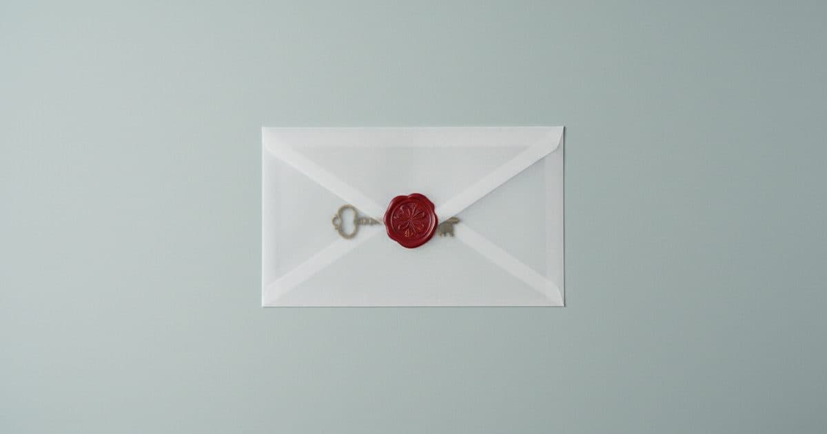 A translucent envelope closed with a red wax seal, a brass key sealed beneath it